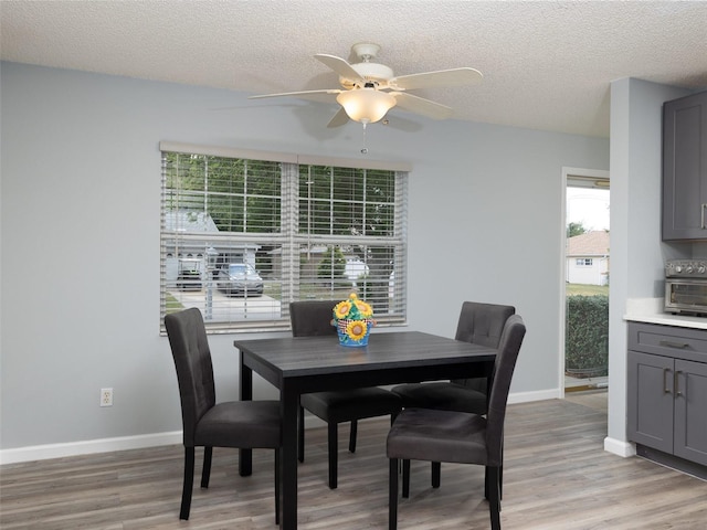 dining area with ceiling fan, a textured ceiling, and light hardwood / wood-style flooring