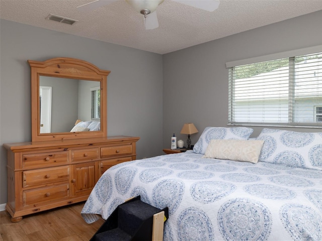 bedroom with a textured ceiling, ceiling fan, and hardwood / wood-style floors