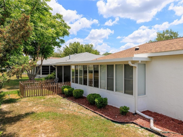 rear view of house with a sunroom and a yard