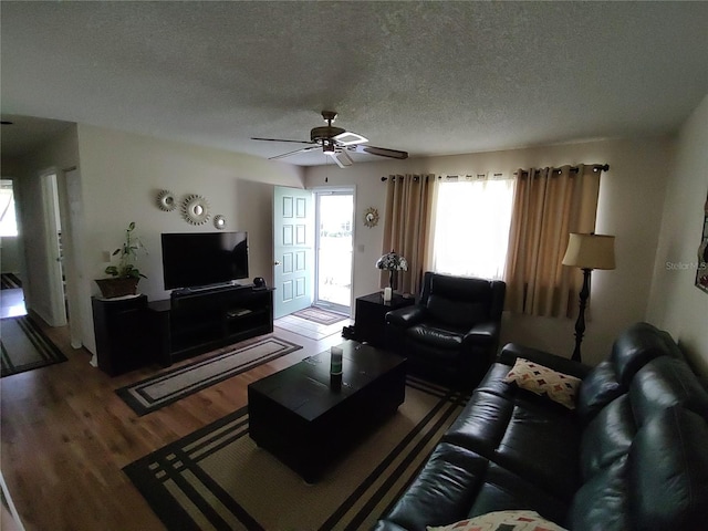 living room with a textured ceiling, a ceiling fan, and wood finished floors