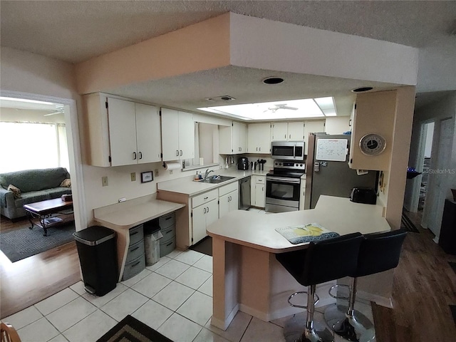 kitchen with a peninsula, light countertops, appliances with stainless steel finishes, and a sink