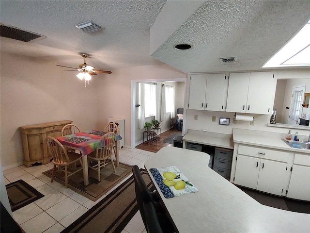 kitchen featuring light countertops, white cabinets, and visible vents