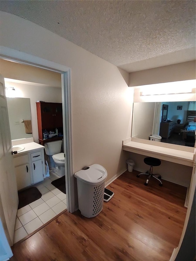 bathroom featuring vanity, toilet, wood finished floors, and a textured ceiling