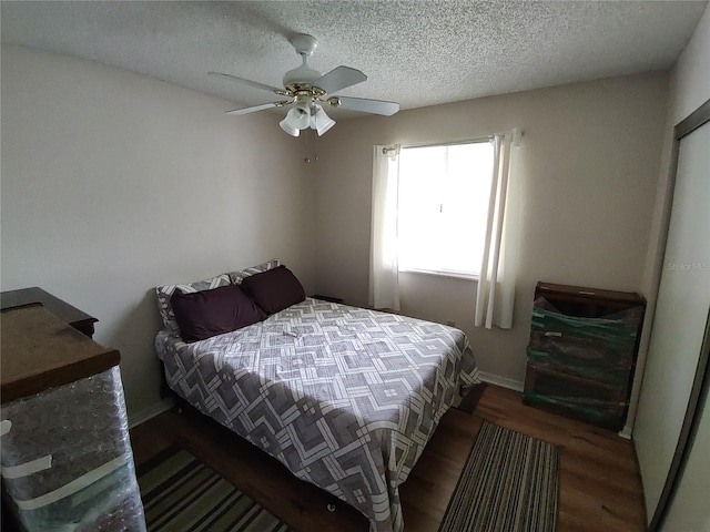 bedroom featuring a ceiling fan, wood finished floors, baseboards, and a textured ceiling