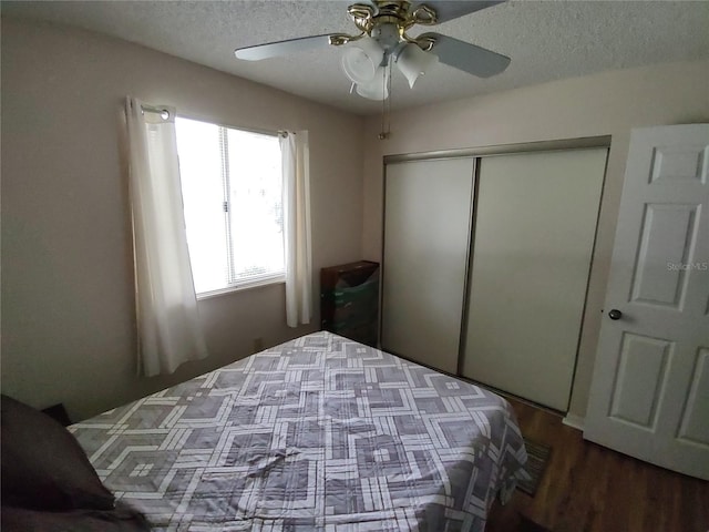 bedroom with a closet, a textured ceiling, a ceiling fan, and wood finished floors