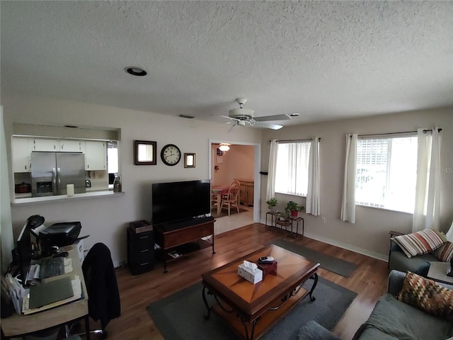 living room with ceiling fan, a textured ceiling, and dark wood-style floors