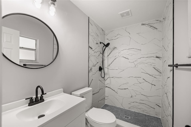 bathroom featuring a tile shower, vanity, and toilet