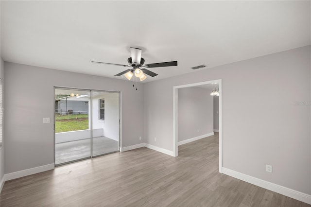 empty room with light hardwood / wood-style floors and ceiling fan with notable chandelier