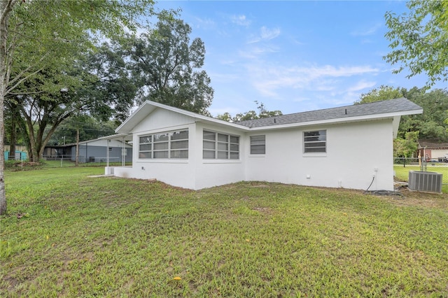 rear view of property with a yard and central AC