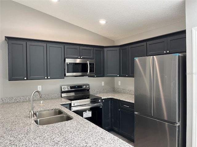 kitchen with vaulted ceiling, stainless steel appliances, light stone countertops, and sink