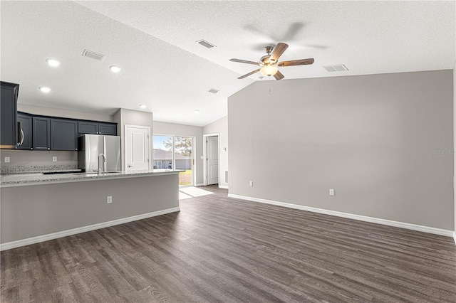 kitchen featuring ceiling fan, appliances with stainless steel finishes, light stone counters, dark hardwood / wood-style flooring, and vaulted ceiling