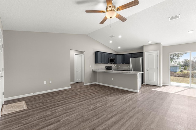 kitchen with vaulted ceiling, appliances with stainless steel finishes, dark hardwood / wood-style floors, sink, and kitchen peninsula