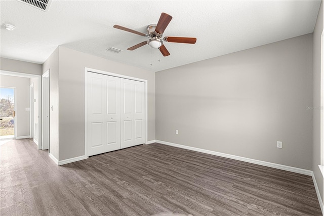 unfurnished bedroom with a closet, a textured ceiling, dark hardwood / wood-style floors, and ceiling fan