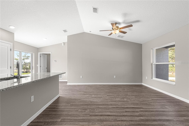 unfurnished living room featuring sink, vaulted ceiling, a textured ceiling, dark hardwood / wood-style flooring, and ceiling fan