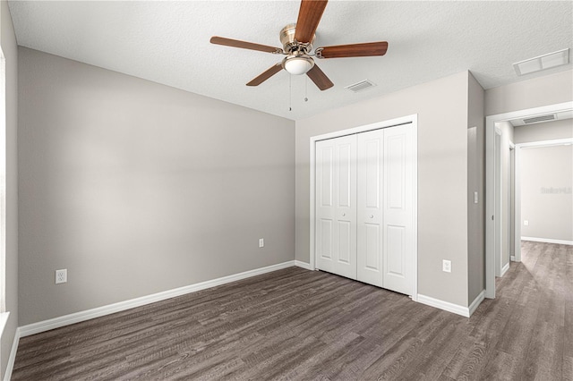 unfurnished bedroom featuring dark hardwood / wood-style flooring, ceiling fan, a closet, and a textured ceiling