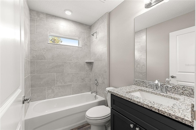 full bathroom featuring tiled shower / bath, vanity, and toilet