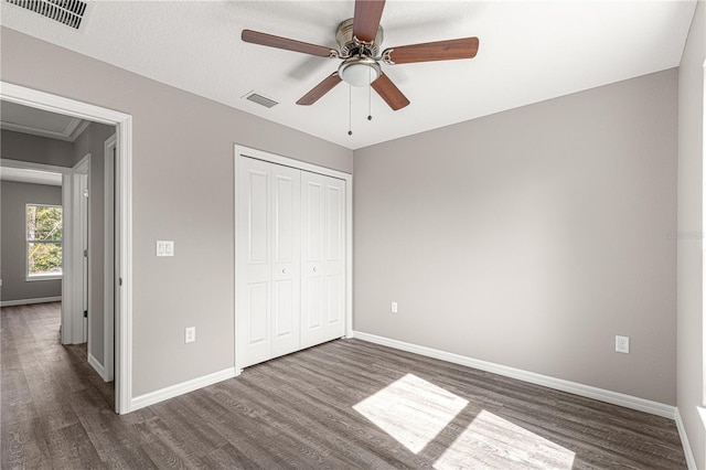 unfurnished bedroom with ceiling fan, dark hardwood / wood-style floors, and a closet