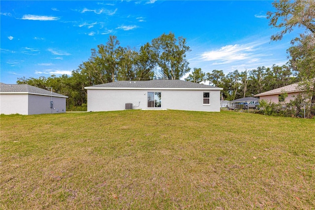 back of house with central AC unit and a lawn