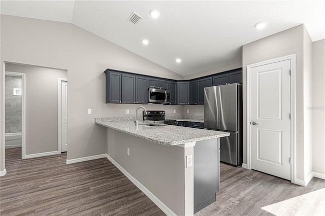 kitchen featuring wood-type flooring, lofted ceiling, sink, kitchen peninsula, and stainless steel appliances