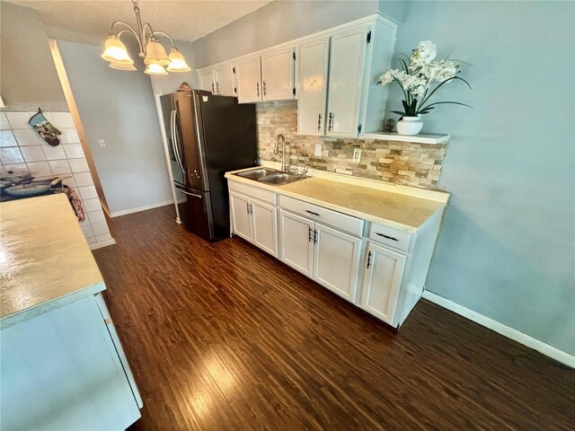 kitchen with dark hardwood / wood-style floors, a notable chandelier, hanging light fixtures, stainless steel refrigerator, and white cabinets