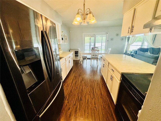 kitchen featuring black range, a healthy amount of sunlight, refrigerator with ice dispenser, and hanging light fixtures