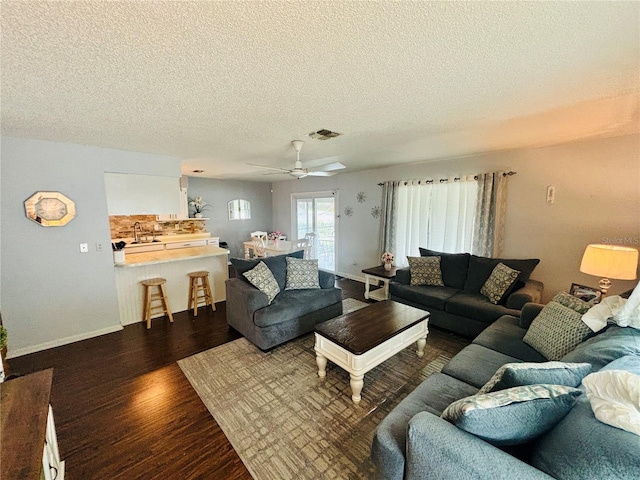 living room with ceiling fan, dark hardwood / wood-style floors, sink, and a textured ceiling