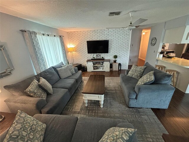 living room with dark wood-type flooring, a textured ceiling, and ceiling fan