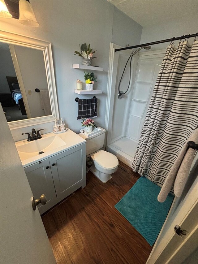 bathroom with walk in shower, toilet, wood-type flooring, and vanity