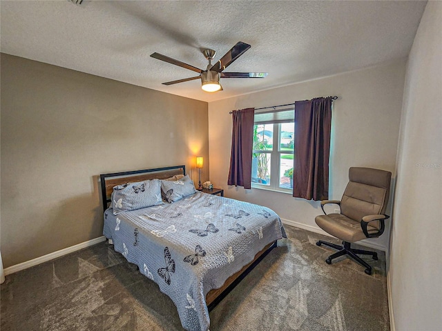 bedroom featuring dark colored carpet, ceiling fan, and a textured ceiling