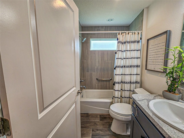 full bathroom with hardwood / wood-style floors, vanity, shower / bath combination with curtain, toilet, and a textured ceiling