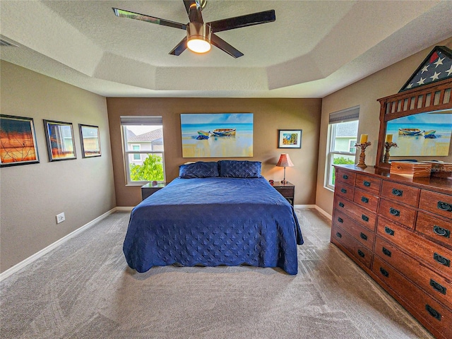 carpeted bedroom featuring a textured ceiling, a raised ceiling, and ceiling fan