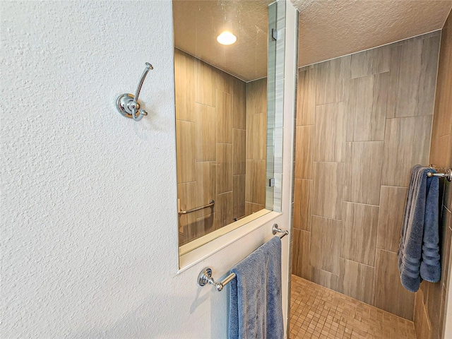 bathroom featuring a textured ceiling and tiled shower