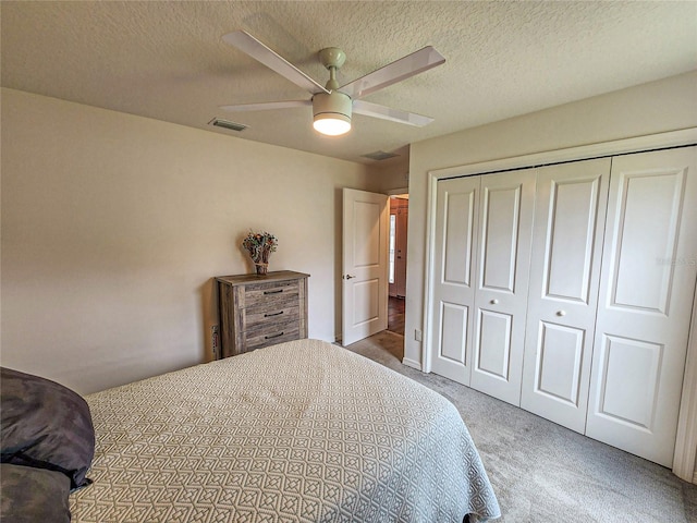 carpeted bedroom featuring ceiling fan, a closet, and a textured ceiling