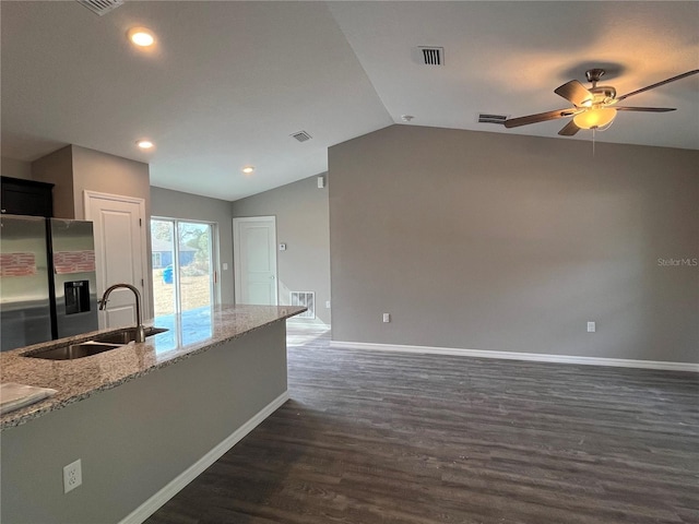 kitchen with vaulted ceiling, sink, stainless steel fridge with ice dispenser, light stone countertops, and dark wood-type flooring