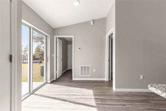 unfurnished room with hardwood / wood-style floors, a wealth of natural light, and vaulted ceiling