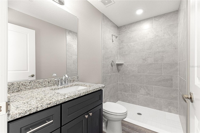 bathroom with vanity, toilet, and tiled shower