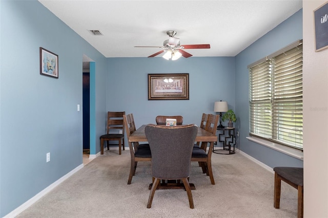 carpeted dining space with ceiling fan