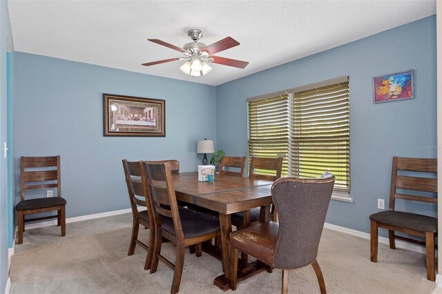 dining area featuring a textured ceiling, light colored carpet, and ceiling fan