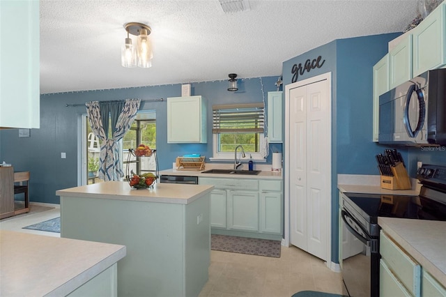 kitchen with appliances with stainless steel finishes, a center island, a textured ceiling, and sink