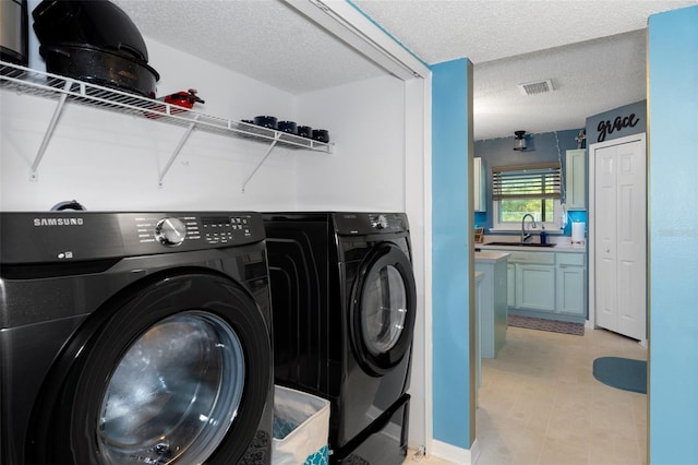 laundry area featuring sink, a textured ceiling, and separate washer and dryer