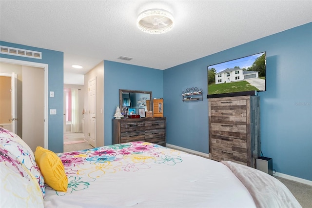 bedroom with a textured ceiling, ensuite bath, and carpet floors