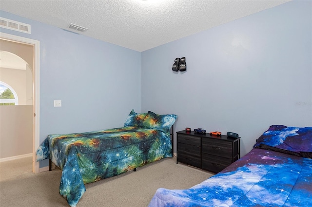 bedroom with light colored carpet and a textured ceiling