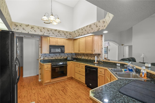 kitchen featuring black appliances, light brown cabinetry, sink, and a towering ceiling