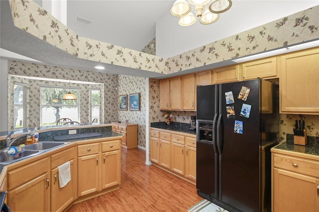 kitchen featuring an inviting chandelier, light hardwood / wood-style flooring, vaulted ceiling, sink, and black fridge with ice dispenser