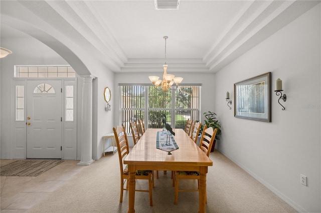 dining area with a tray ceiling, decorative columns, an inviting chandelier, and light colored carpet