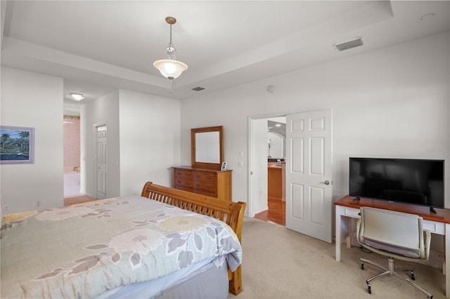 carpeted bedroom featuring a tray ceiling and connected bathroom