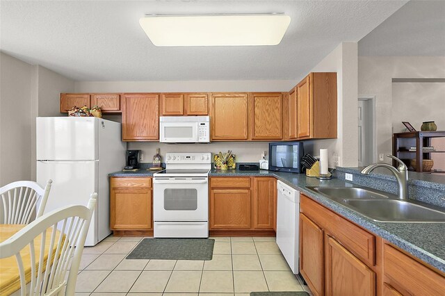 kitchen featuring white appliances, sink, light tile patterned flooring, and a textured ceiling