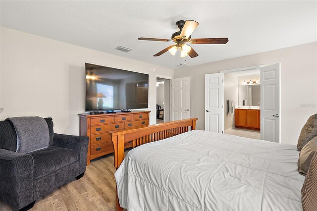 bedroom with ceiling fan, light hardwood / wood-style floors, and ensuite bath