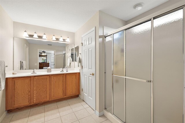 bathroom with a shower with shower door, ceiling fan, vanity, and tile patterned floors