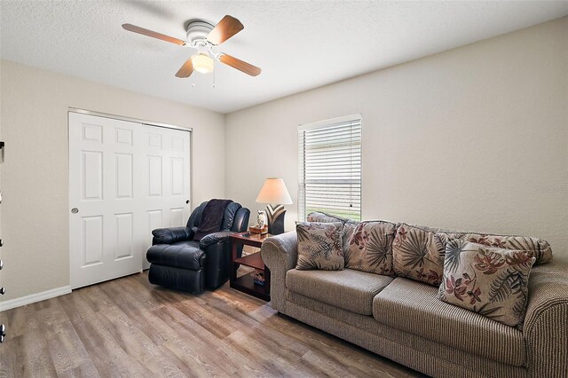 living room featuring light wood-type flooring, a textured ceiling, and ceiling fan